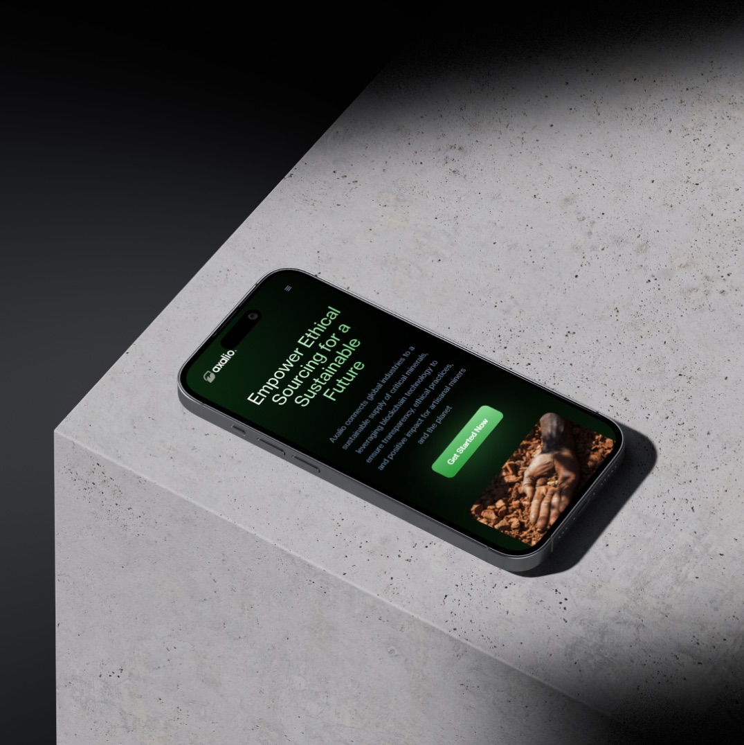Phone lying on a concrete block showing the mobile Axalio hero with a green Get Started Now button